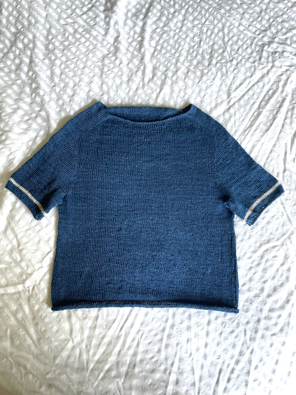 completed knit shirt, a little cropped and with elbow-length sleeves, dark navy with a thin white stripe at the end of each sleeve